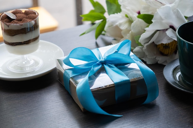 Coffret cadeau avec des bonbons artisanaux au chocolat sur une table de café avec une tasse et un dessert