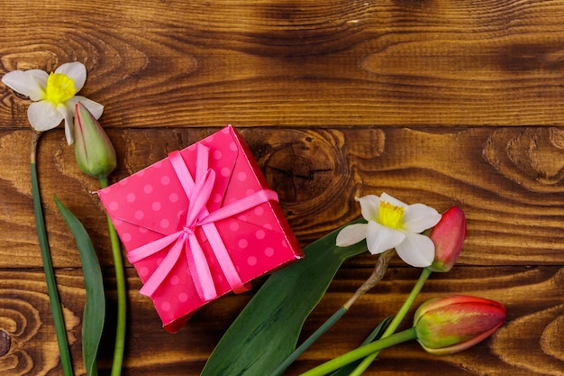 Coffret cadeau et bouquet de tulipes rouges et de jonquilles sur fond en bois Concept de la Saint-Valentin Fête des femmes Fête des mères et anniversaire Vue de dessus espace de copie