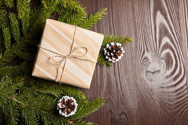 Coffret cadeau avec branche d'arbre de Noël vert et cônes sur fond de bois marron