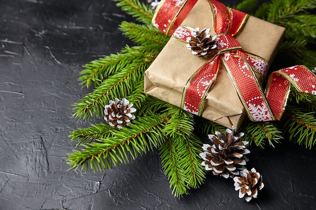 Coffret cadeau avec branche d'arbre de Noël vert et cônes sur fond noir