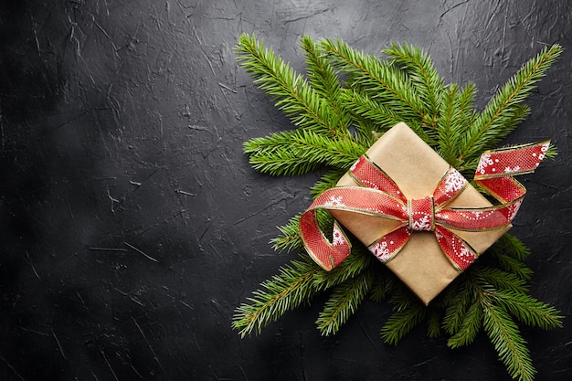 Coffret cadeau avec une branche d'arbre de Noël verte sur fond sombre avec vue de dessus de l'espace de copie