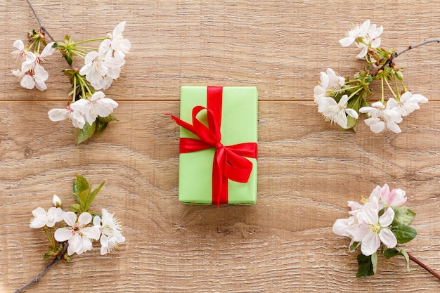 Coffret cadeau avec des branches de cerisier en fleurs et de pommiers sur le fond en bois. Vue de dessus. Concept de donner un cadeau en vacances.