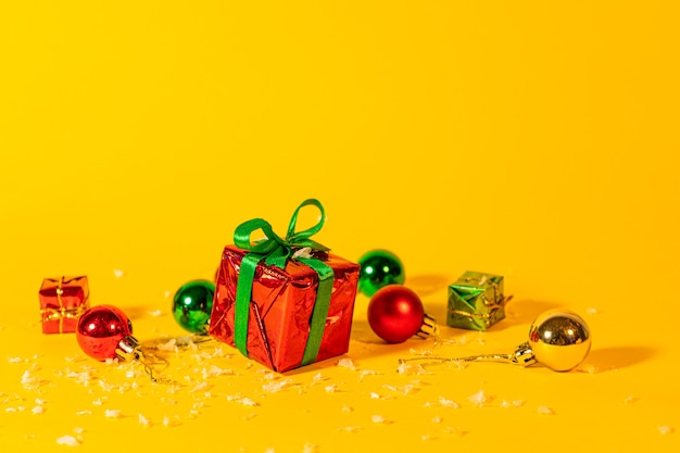 Coffret cadeau avec un cadeau de Noël sur fond jaune, parmi les décorations du nouvel an.