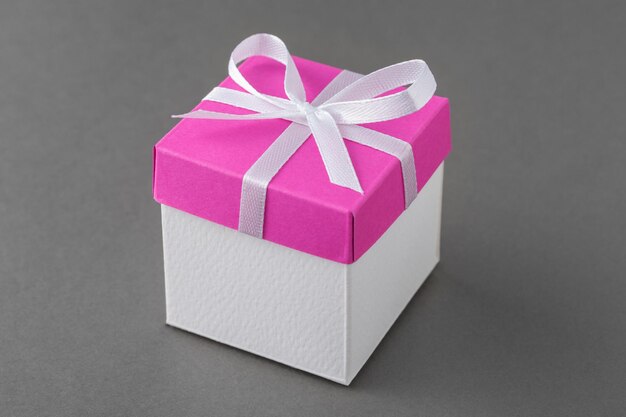 Coffret cadeau avec couvercle rose et noeud en soie sur fond gris