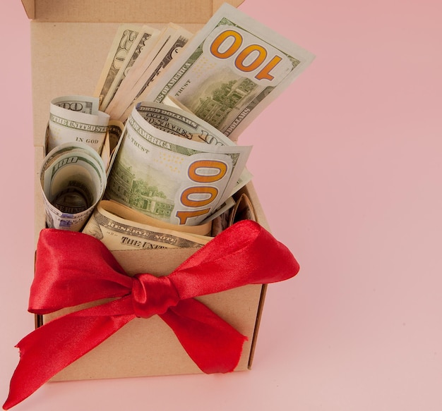 Coffret cadeau avec des dollars sur fond rose gros plan