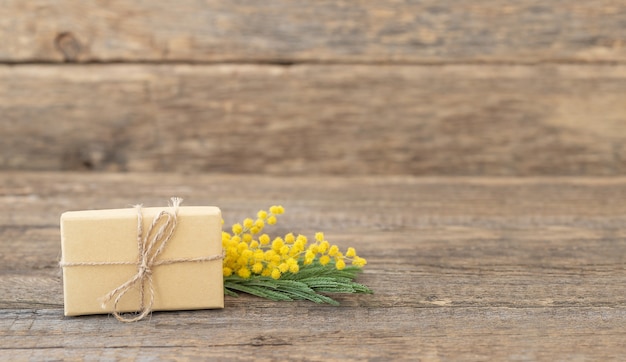 Coffret cadeau écologique avec un brin de mimosa sur une surface en bois