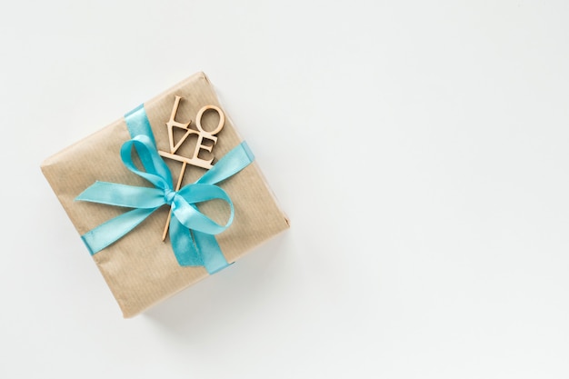 Coffret cadeau emballé dans du papier brun avec un ruban bleu sur blanc