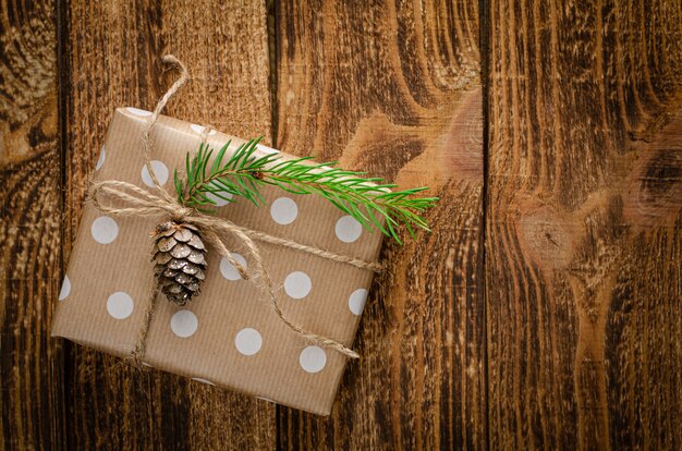 Coffret cadeau enveloppé dans du papier kraft avec sapin et cône sur fond en bois rustique