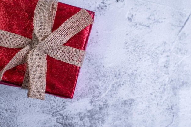 Coffret cadeau enveloppé dans du papier rouge sur une table en béton