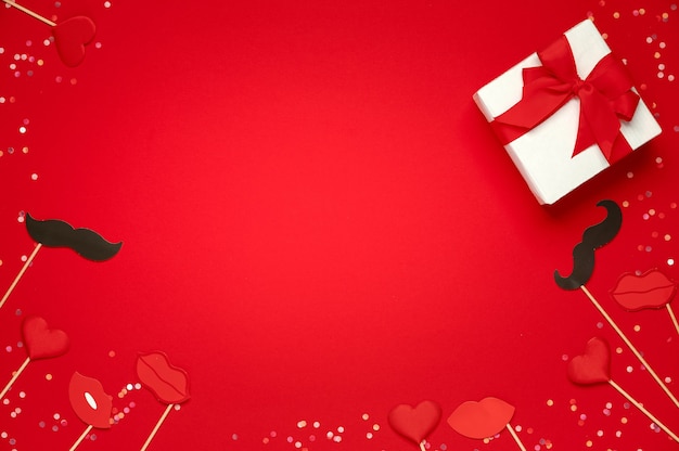 Coffret cadeau et lèvres douces coeurs et moustache en papier sur fond rouge. Modèle de la Saint-Valentin