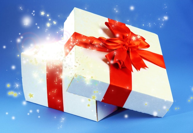 Coffret cadeau avec une lumière vive dessus sur fond bleu