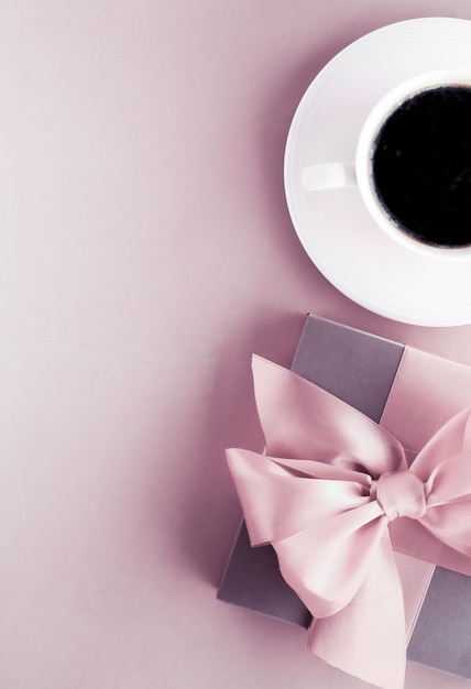 Coffret cadeau de luxe et tasse à café sur fond rose blush design flatlay pour des vacances romantiques et une surprise d'anniversaire