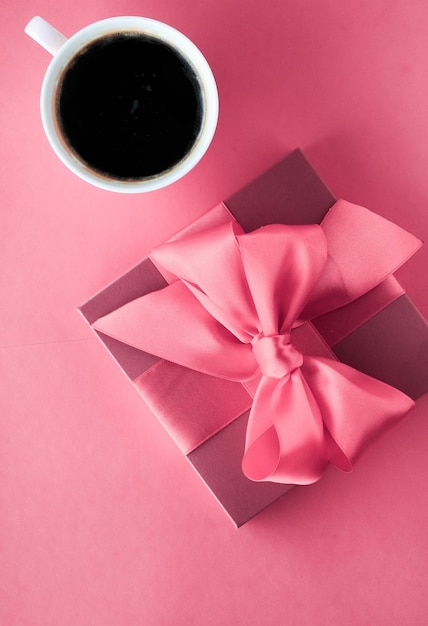 Coffret cadeau de luxe et tasse à café sur fond rose design plat pour une surprise matinale de vacances romantiques