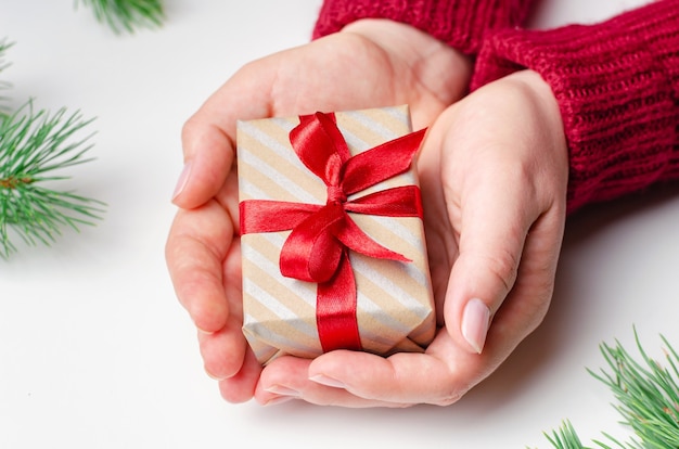 Coffret cadeau de Noël avec un arc rouge dans les mains des femmes sur fond blanc