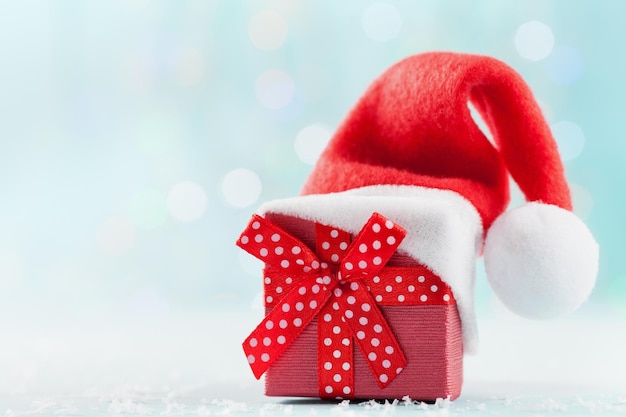 Coffret cadeau de Noël avec chapeau de Père Noël sur fond turquoise bokeh Carte de vœux de Noël