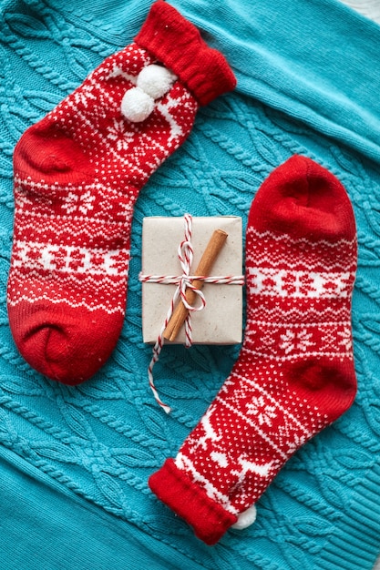 Coffret cadeau de Noël et chaussettes rouges, un pull en tricot bleu et une guirlande avec des cônes