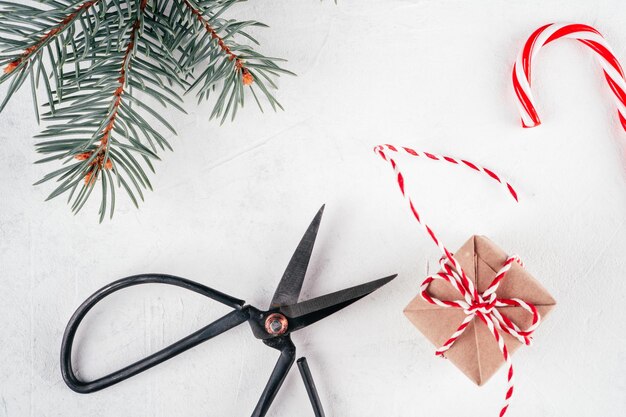 Coffret cadeau de Noël et ciseaux sur fond de béton blanc avec branche d'arbre de Noël. Vue de dessus