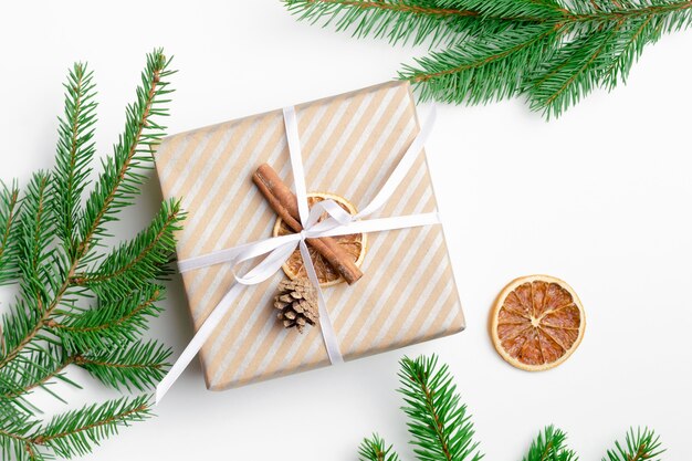 Coffret cadeau de noël décoré avec des branches de sapin sur blanc