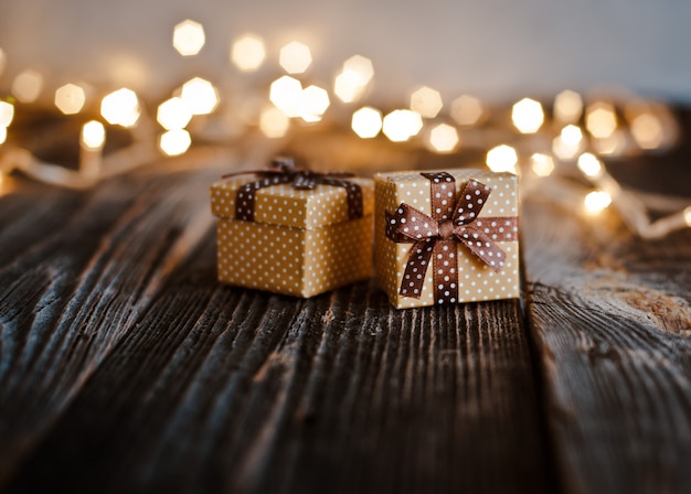 Coffret cadeau de Noël posé sur une table en bois, bokeh de lumières festives.