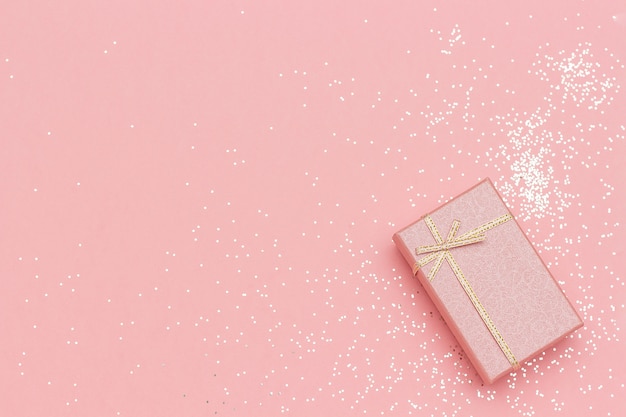 Coffret cadeau avec noeud en coin sur fond pastel rose de style minimal