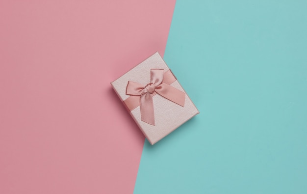 Coffret cadeau avec noeud sur fond pastel bleu-rose. Composition pour Noël, anniversaire ou mariage. Vue de dessus