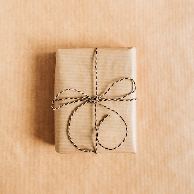 Coffret cadeau avec noeud sur la surface du papier craft. Mise à plat, vue de dessus