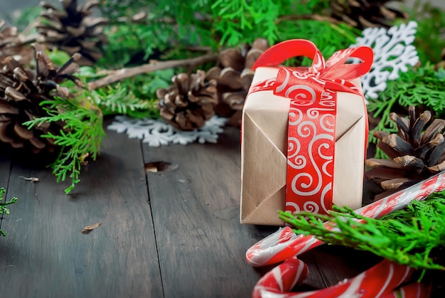 Coffret cadeau noué avec un ruban rouge, des branches de sapin, des bonbons