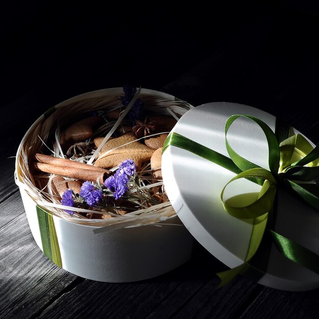 coffret cadeau de pains d'épice faits maison avec de la cannelle et des fleurs sur fond noir