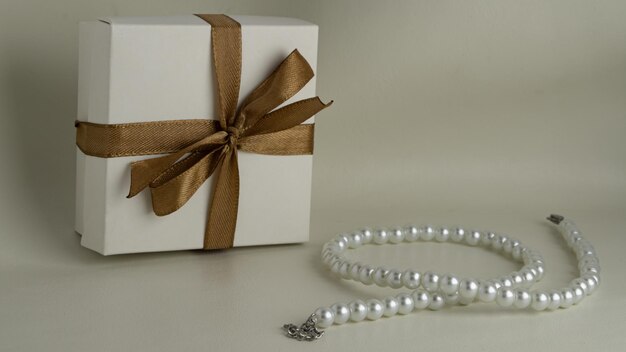 coffret cadeau avec ruban et collier de perles sur cuir texturé
