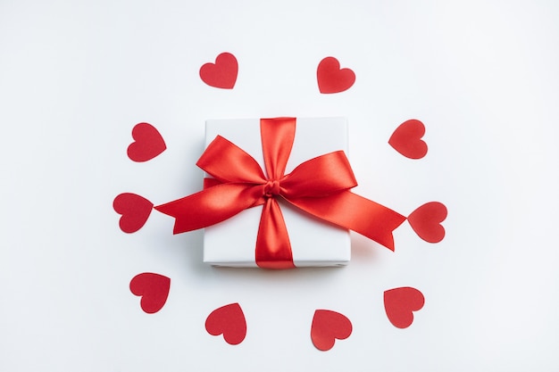 Coffret cadeau avec ruban rouge et coeurs sur fond blanc Carte de Saint Valentin