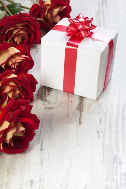 Coffret cadeau sur un tableau blanc avec des roses rouges