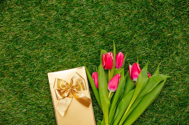 Coffret cadeau avec des tulipes sur l'herbe verte dans un jardin