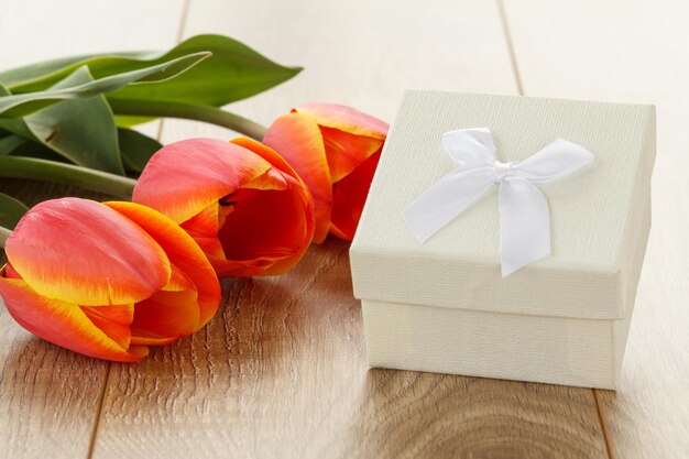 Coffret cadeau avec des tulipes rouges sur les planches de bois. Notion de carte de voeux.