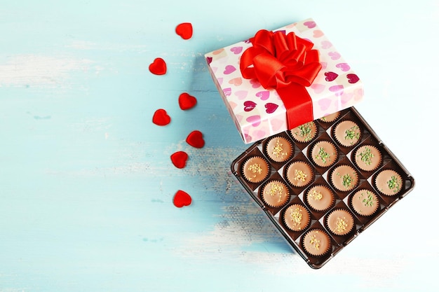 Coffret avec de délicieux bonbons au chocolat sur table en bois