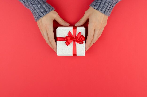 Coffret doré dans des mains féminines sur fond rouge