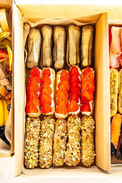 Coffret gastronomique aux éclairs sucrés : mousse au fromage, fraises fraîches, crème enrobée de chocolat, chapelure de pistache