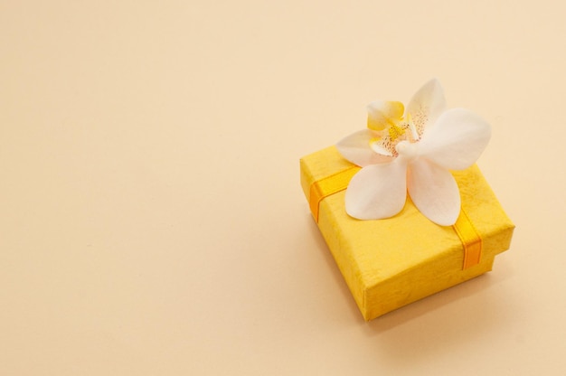 Coffret jaune avec fleur d'orchidée sur fond beige