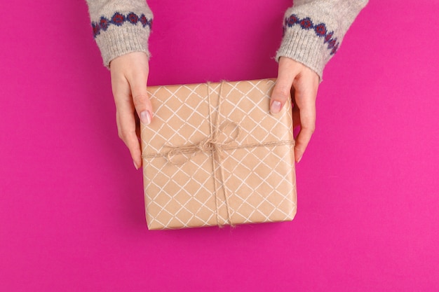 Coffret en mains féminines sur fond rose