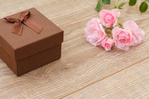 Coffret marron avec de belles roses en arrière-plan. Concept de donner un cadeau en vacances. Vue de dessus.