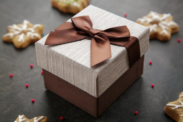 Coffret marron avec présent sur fond sombre avec des biscuits de Noël au gingembre