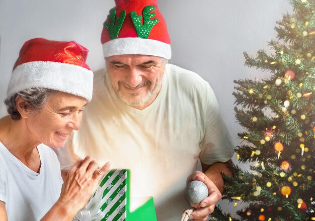 Coffret ouvert de couple de personnes âgées près de l'arbre de Noël