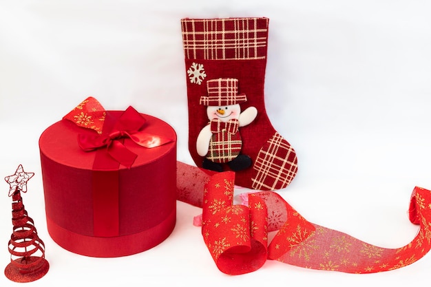 Coffret rouge avec arc rouge, chaussette et sapin de Noël sur fond blanc