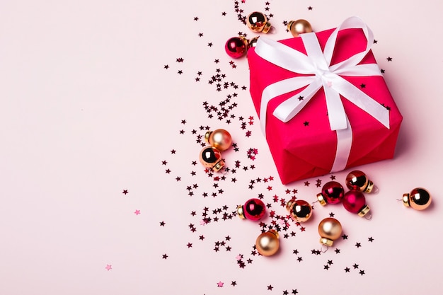 Coffret rouge sur fond pastel. Boules de Noël dorées et rouges.