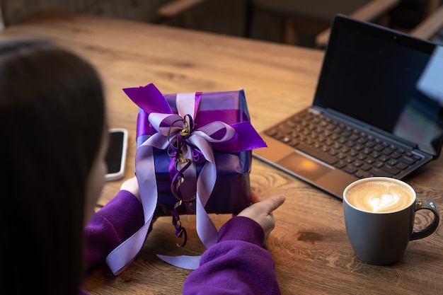 Coffret violet dans les mains d'une femme dans un pull violet