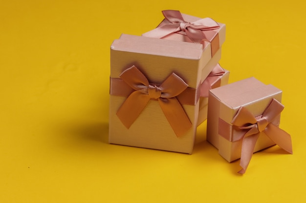 Coffrets cadeaux avec des arcs sur fond de studio jaune. Composition pour Noël, anniversaire ou mariage.