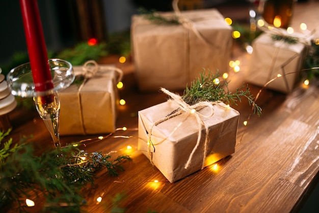 Coffrets cadeaux artisanaux de fête avec garlad et bougies sur la table en bois