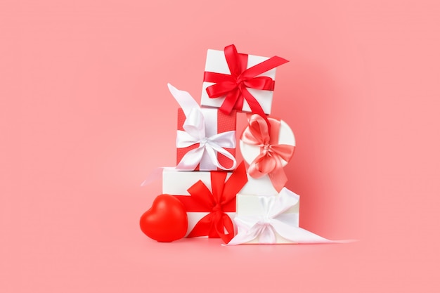 Photo coffrets cadeaux blancs avec des rubans de satin rouges sur fond rose. cadeaux festifs pour la saint-valentin, la journée internationale de la femme, le mariage ou les fiançailles.