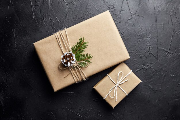 Coffrets cadeaux et branche d'arbre de Noël vert avec cône sur fond sombre vue de dessus