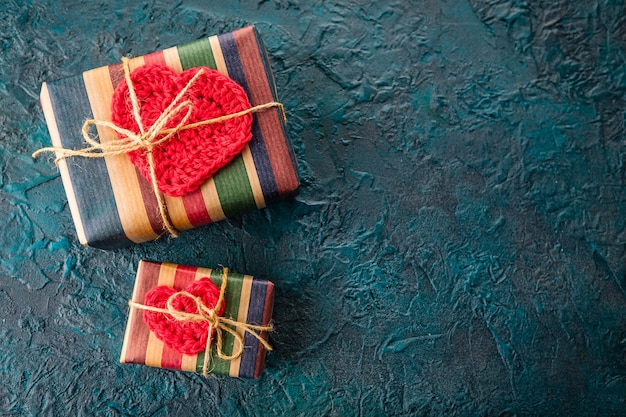 Coffrets cadeaux et coeurs de valentine au crochet sur fond sombre.