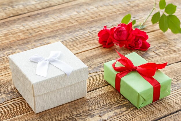 Coffrets cadeaux enveloppés de rubans sur de vieilles planches en bois décorées de roses rouges. Vue de dessus.